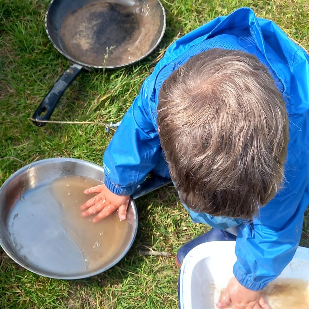 A child playing with pots and pans outdoors