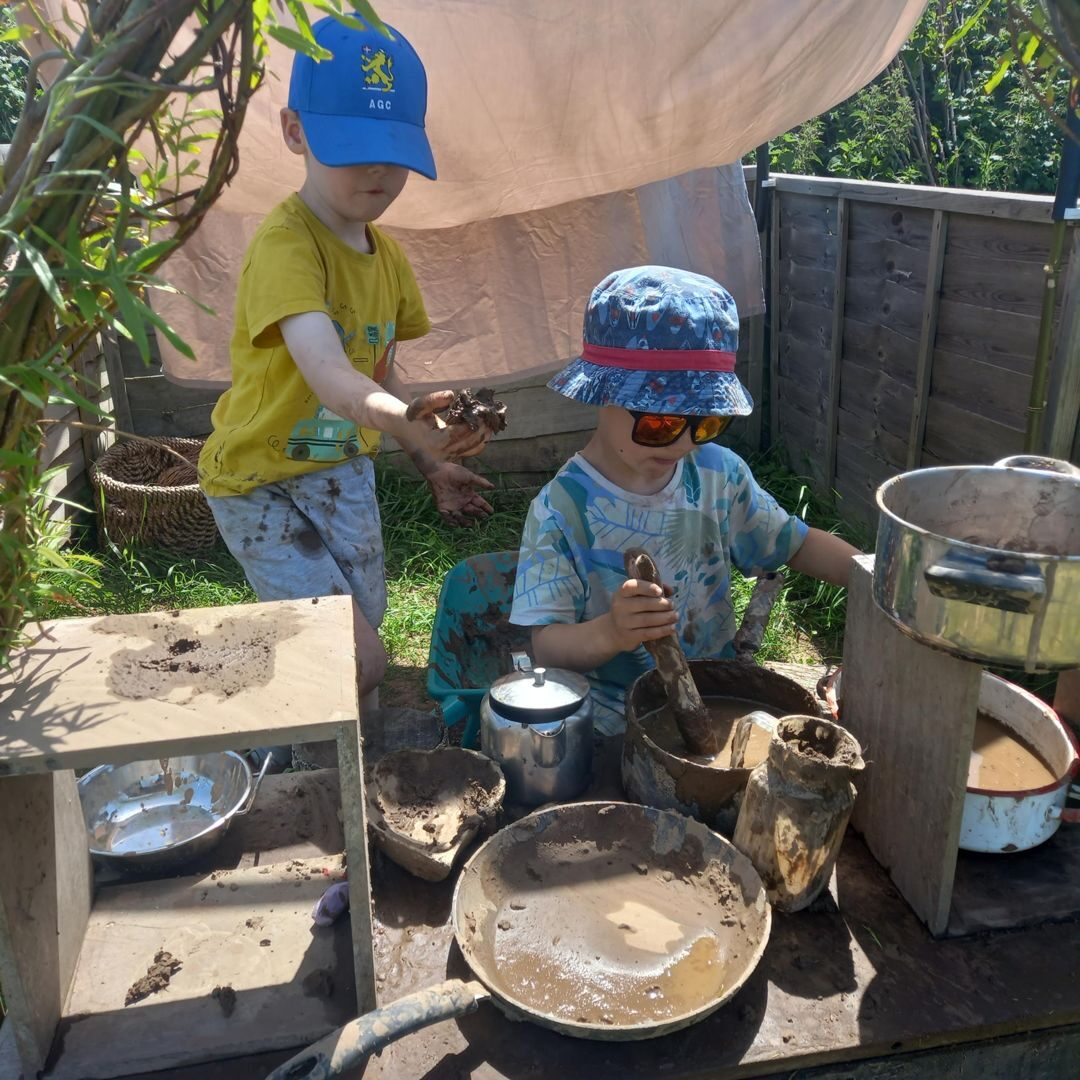 Children cooking up mud and water in metal pots